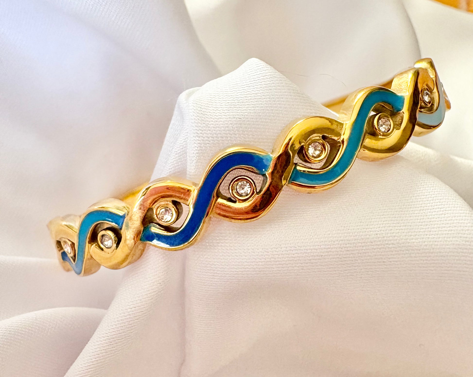 Gold bracelet with blue accents on a white mannequin hand