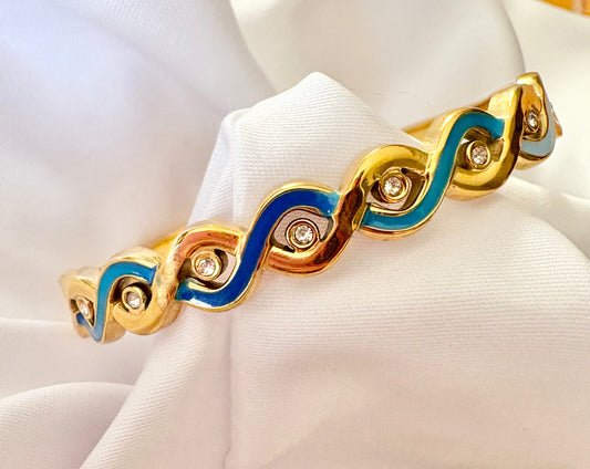 Gold bracelet with blue accents on a white mannequin hand