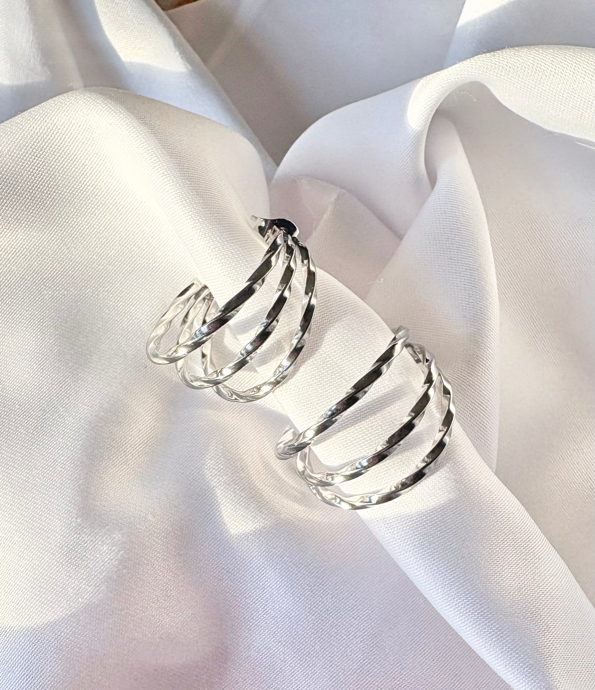 Silver spiral earrings on a white fabric background