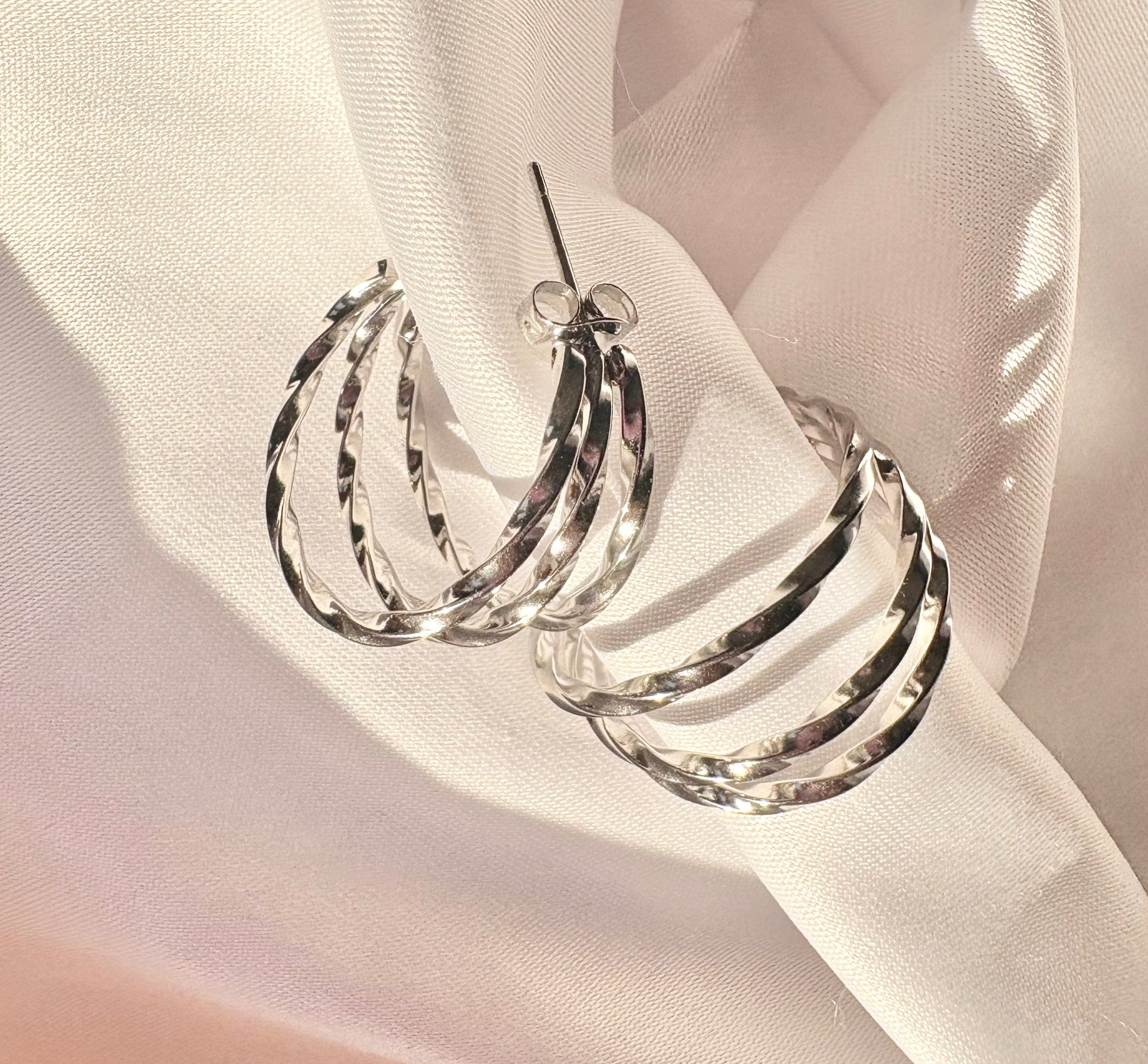 Silver hoop earrings on a light fabric background