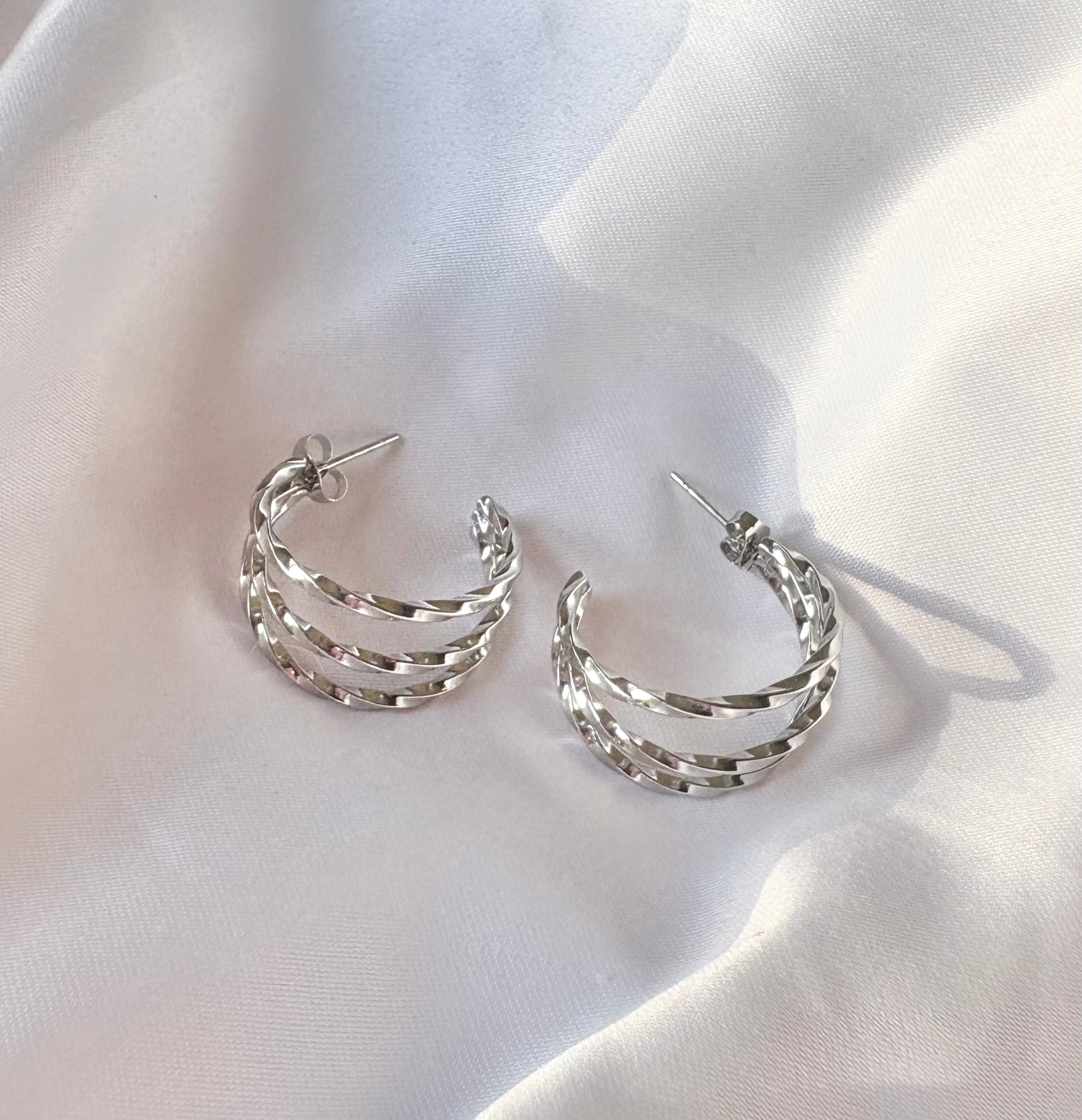 Silver hoop earrings on a white fabric background