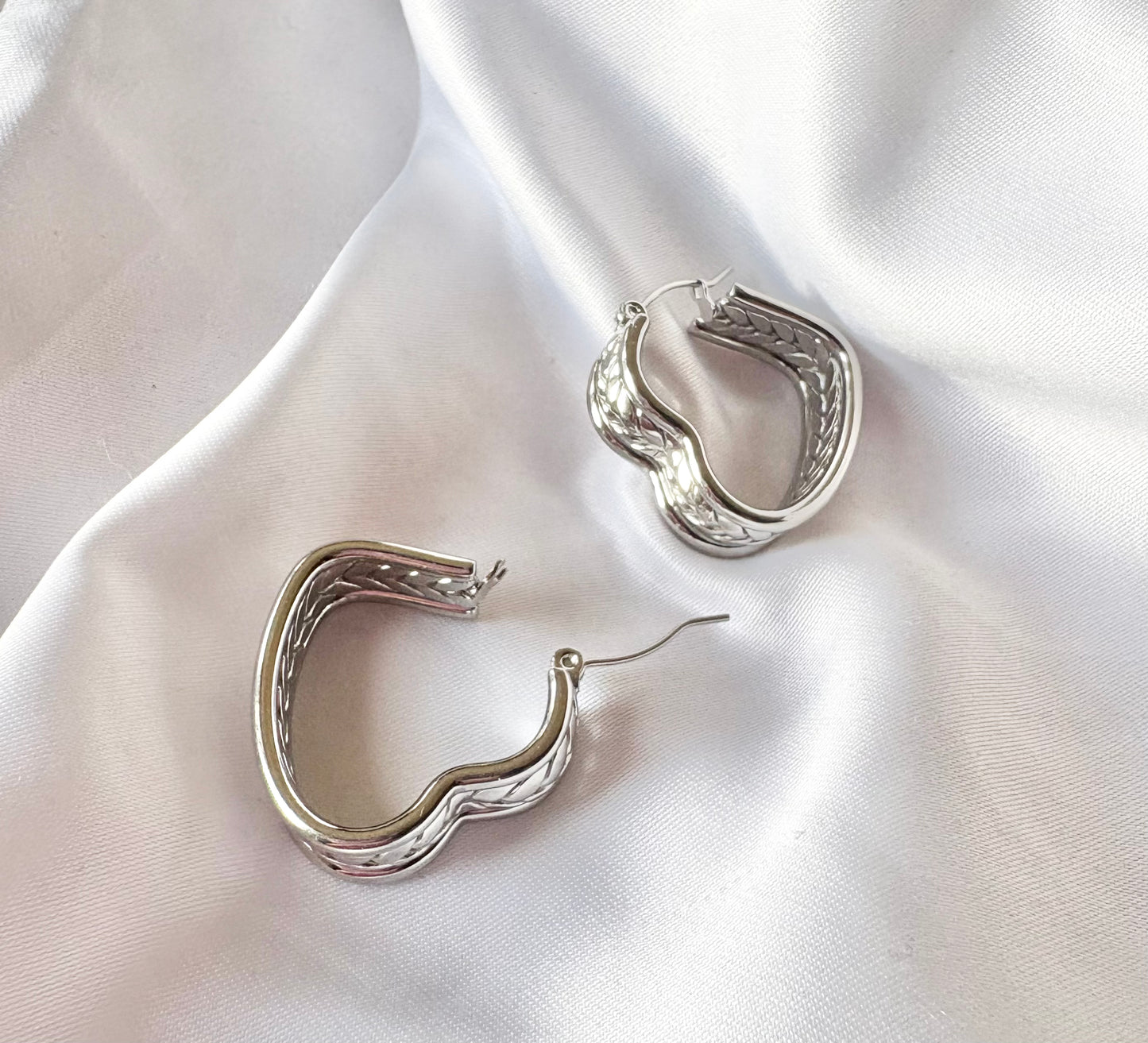 Silver hoop earrings on a white fabric background