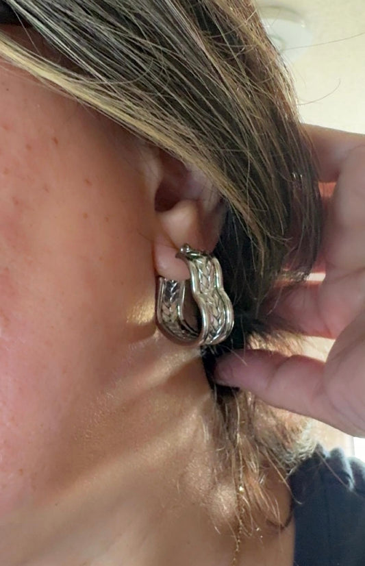 Close-up of a person wearing a silver hoop earring.