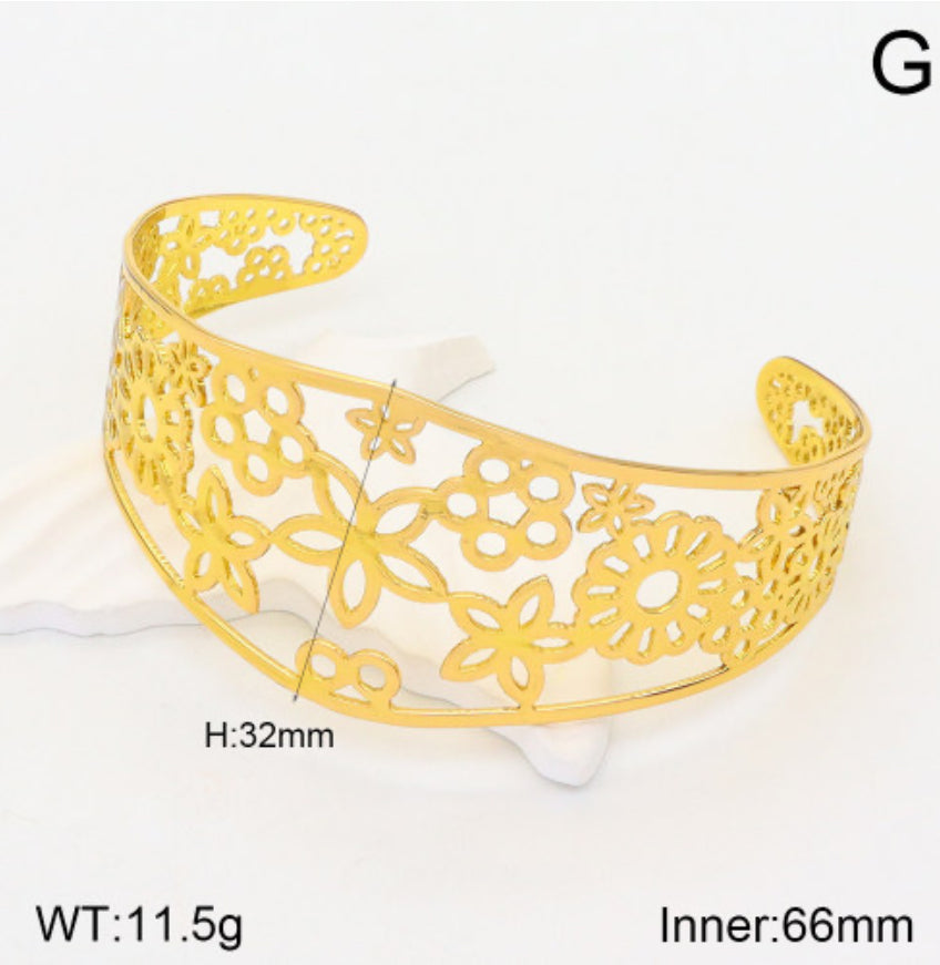 Gold bracelet with floral cut-out design on a white background