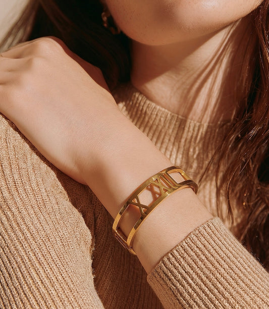 Close-up of a person wearing a gold bracelet on a blurred background