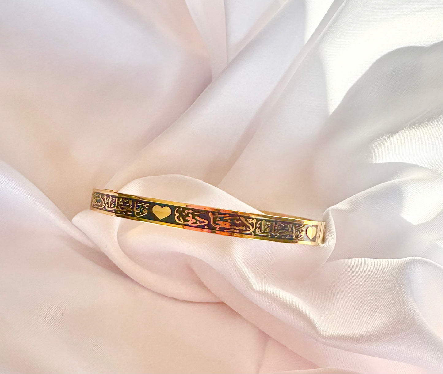 Gold bracelet withArabic Calligraphy designs on a soft white fabric background