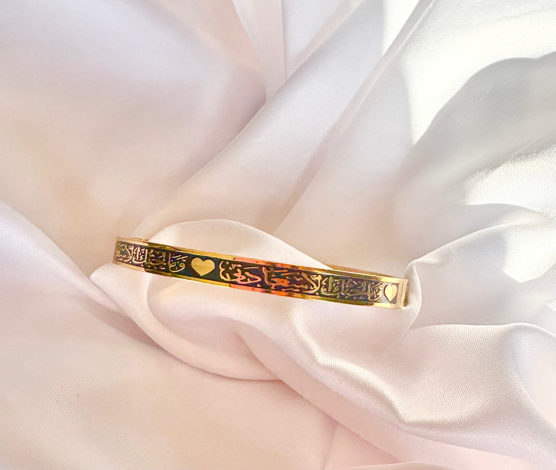 Gold bracelet withArabic Calligraphy designs on a soft white fabric background