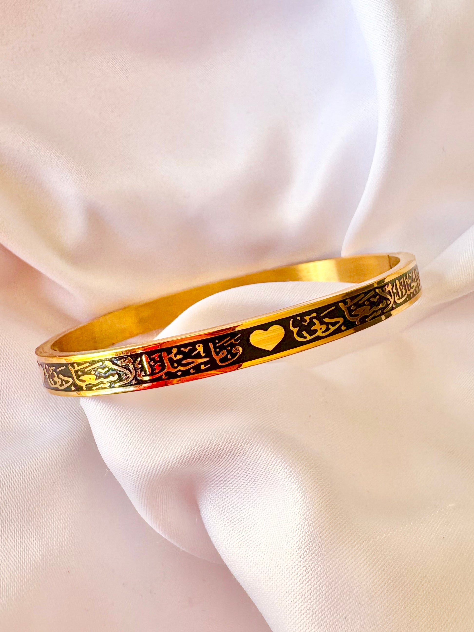 Gold bracelet with Arabic Calligraphy designs on a soft fabric background