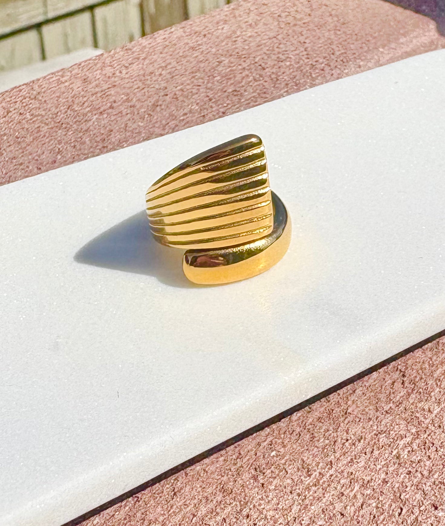 A gold-colored ring with a textured, ridged triangular top and a smooth band.