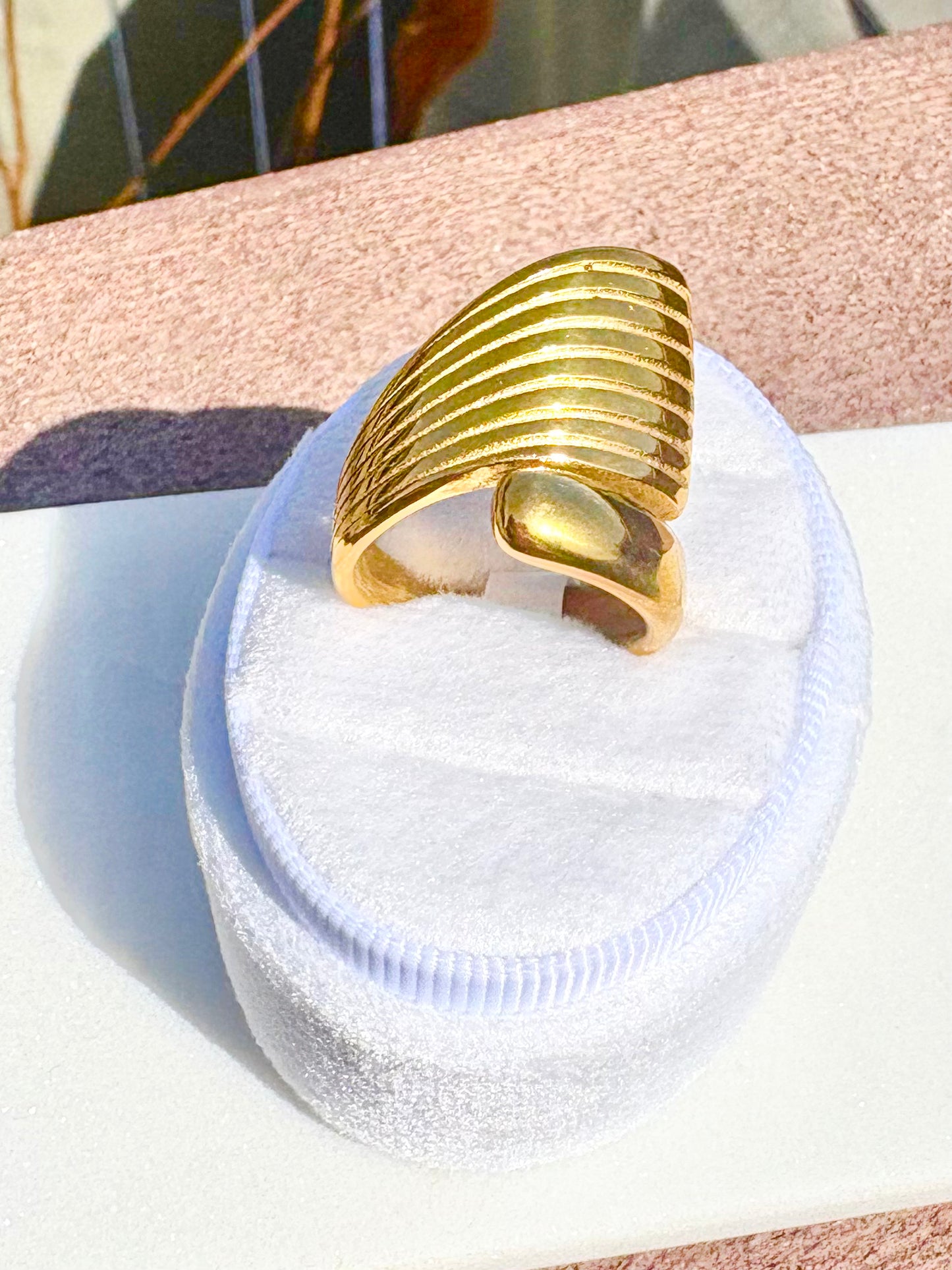 A wide, chunky gold ring with a ribbed, segmented crescent-like design