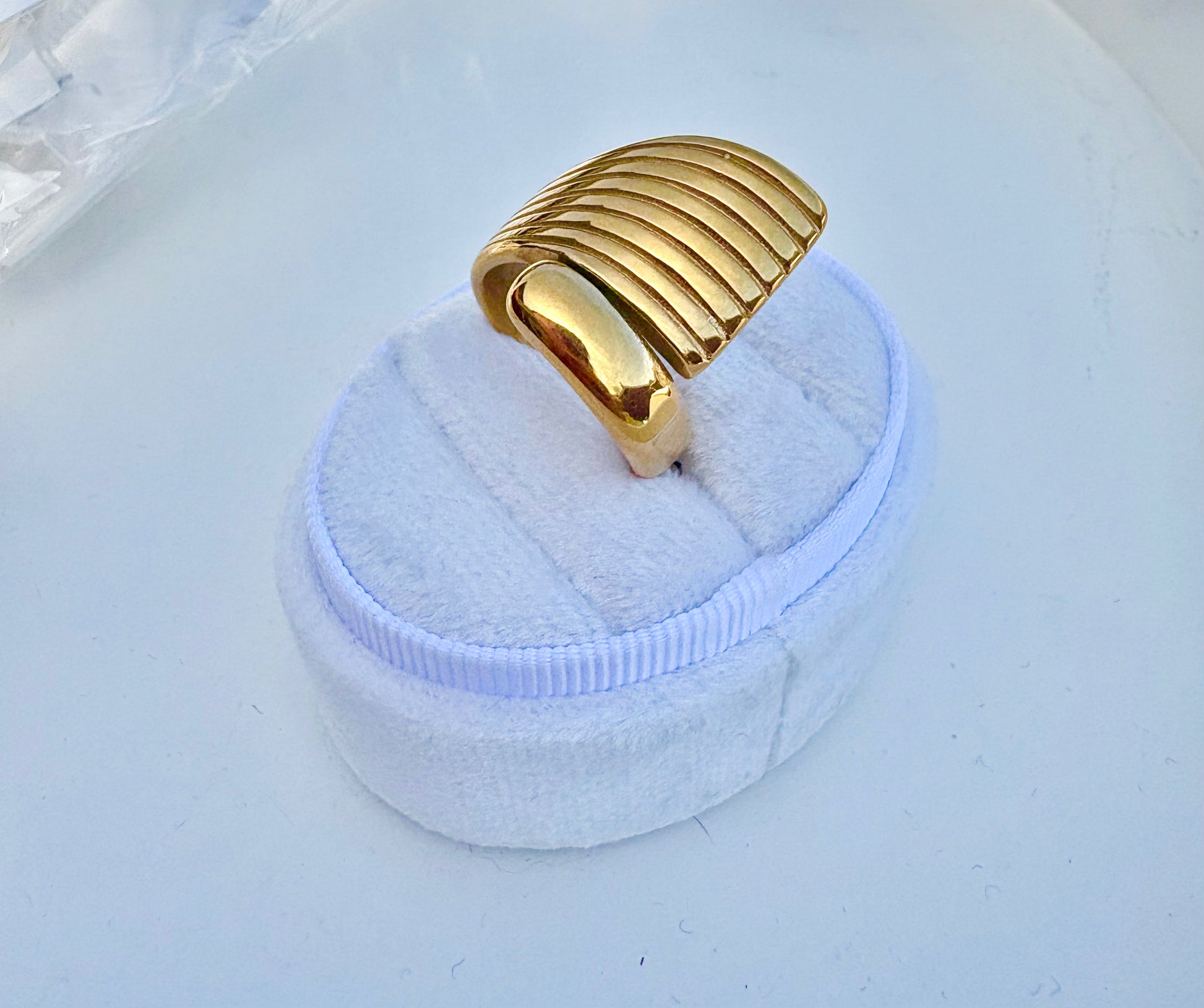 A wide, chunky gold ring with a ribbed, curved top