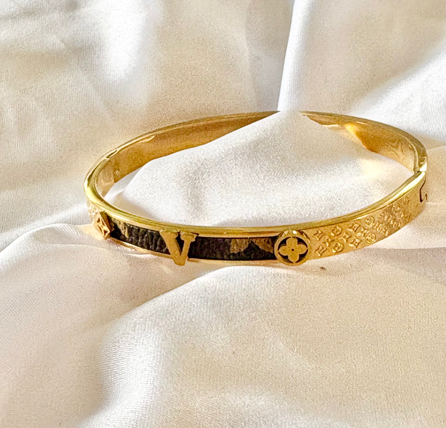 Gold bracelet with intricate designs on a white fabric background
