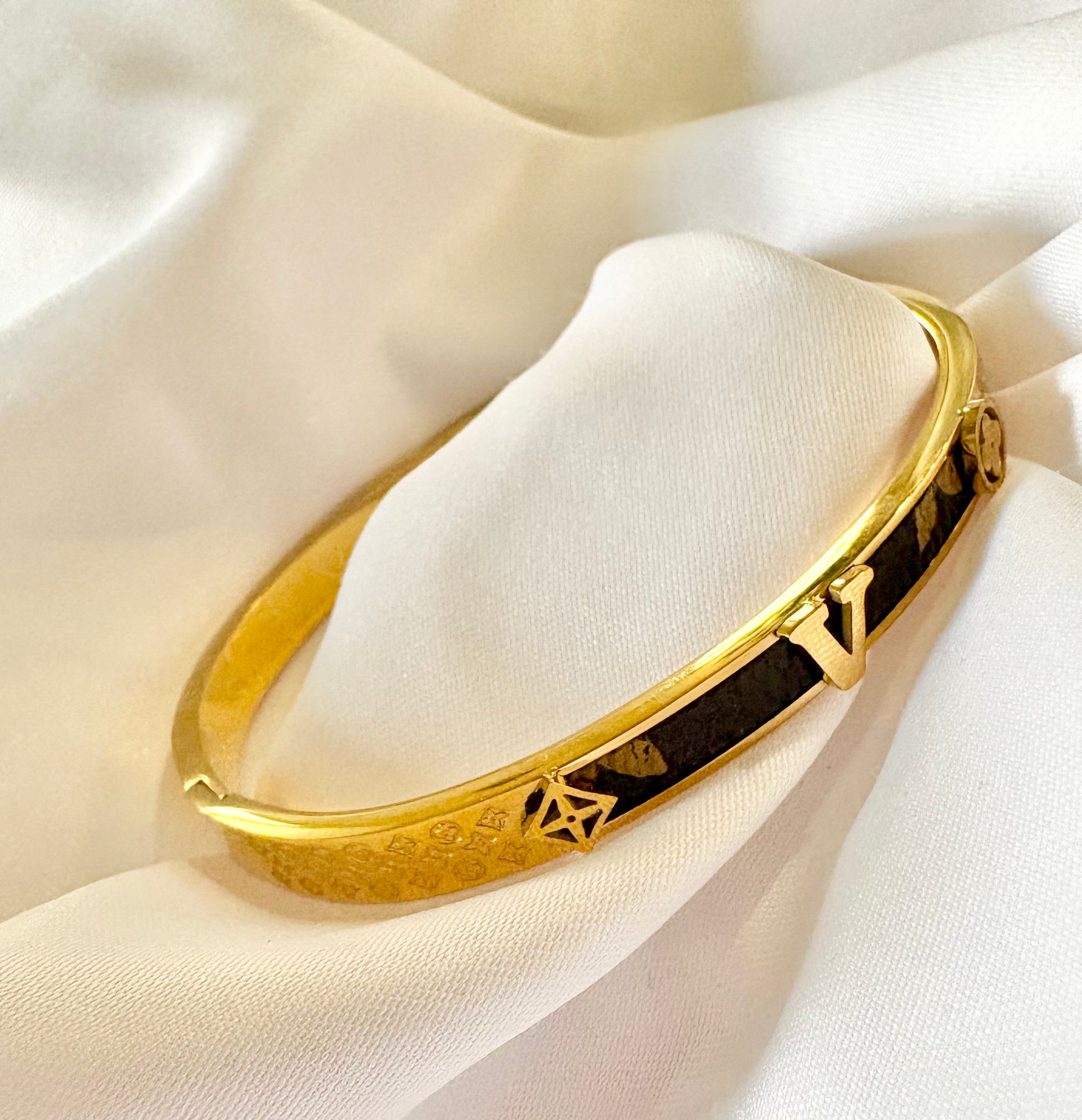 Gold bracelet with brown accents on a white fabric background