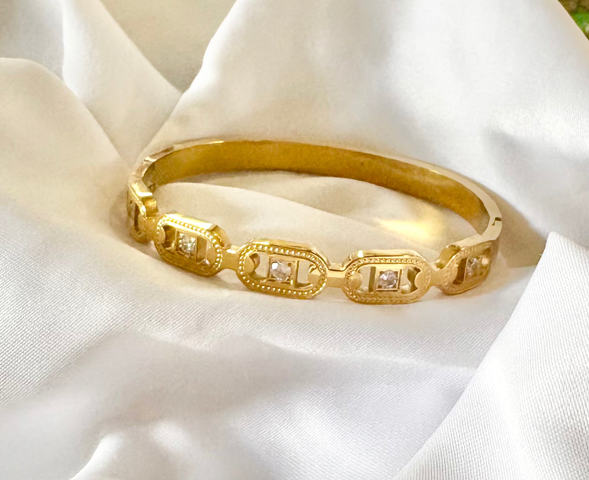 Gold bracelet with diamond accents on a white fabric background