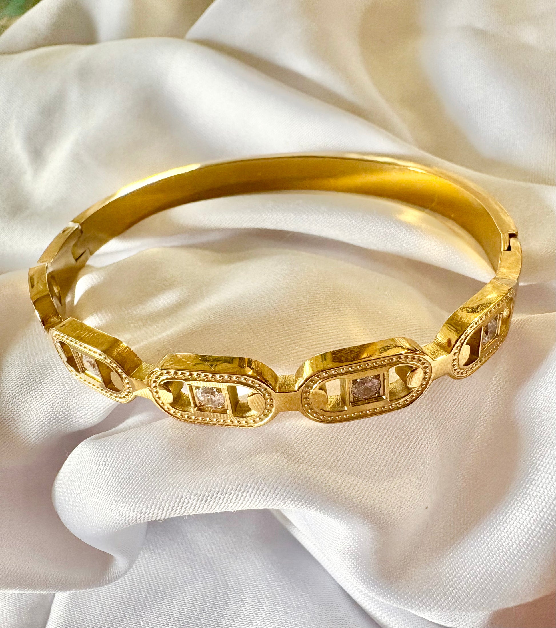 gold bangle with zircon stones on a white fabric