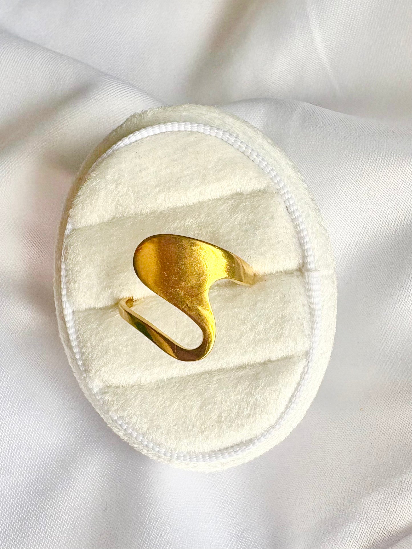 White round pad with gold wave design on a white fabric background