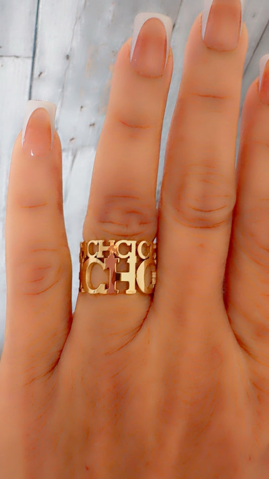 Gold ring with 'CH' text on a hand against a light background