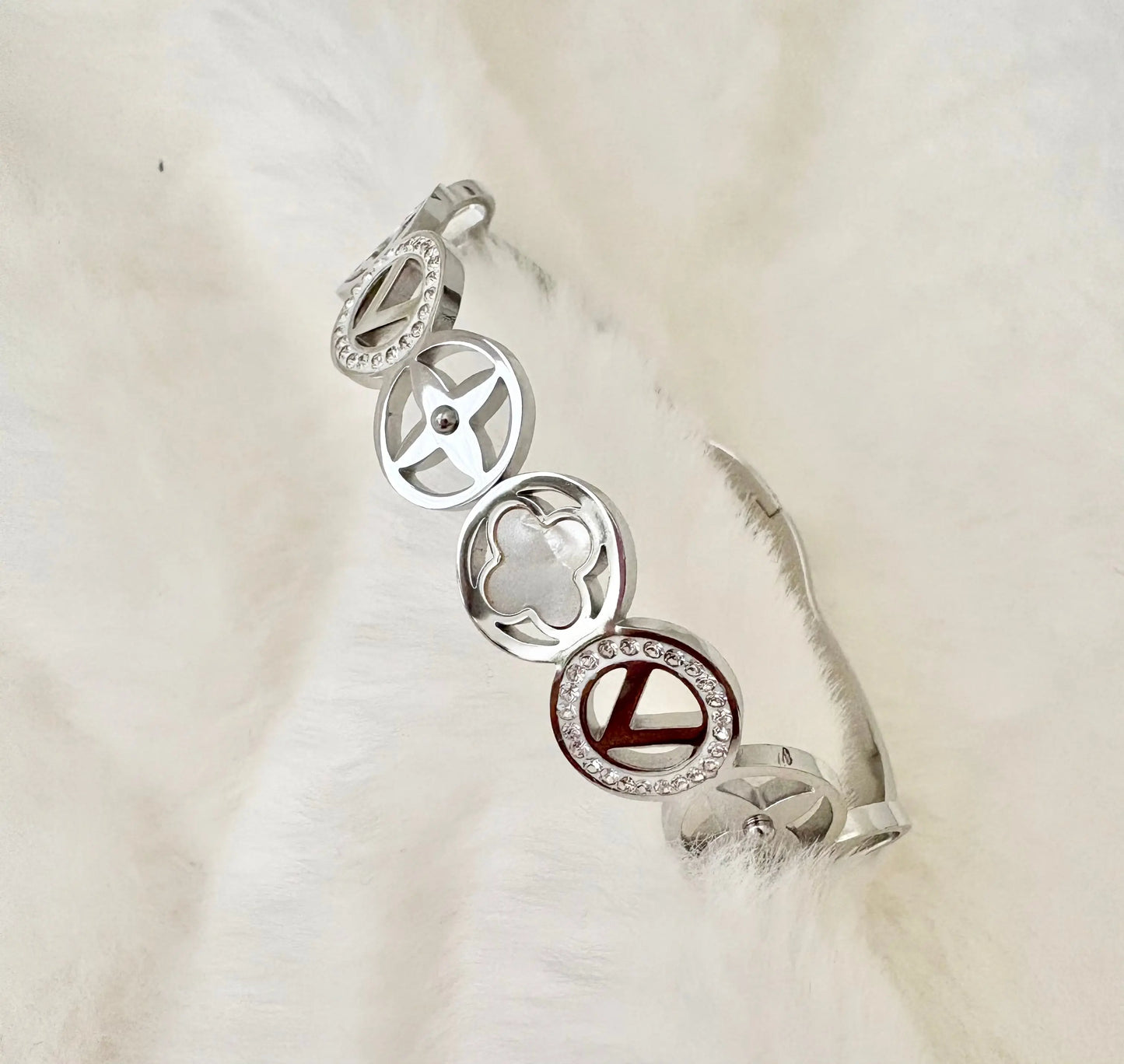 A silver-toned bangle bracelet featuring four interlocking circular charms