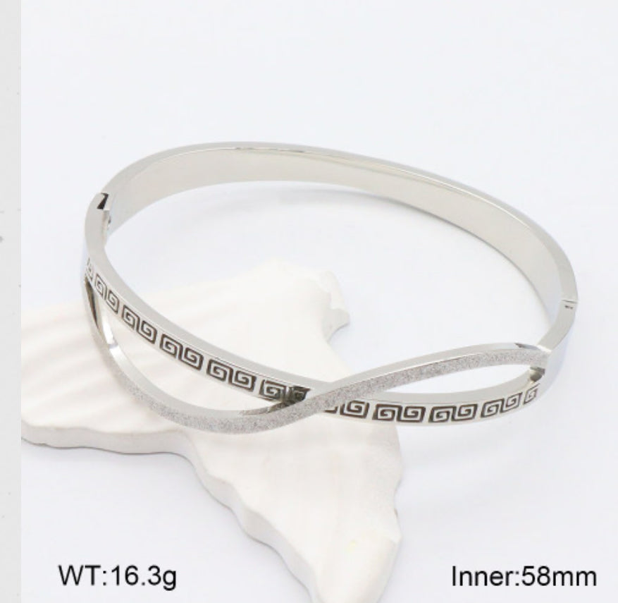 Silver bangle with geometric pattern on a white background