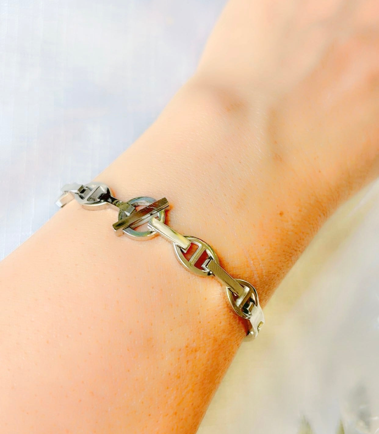 Silver chain bracelet on a wrist with a light background