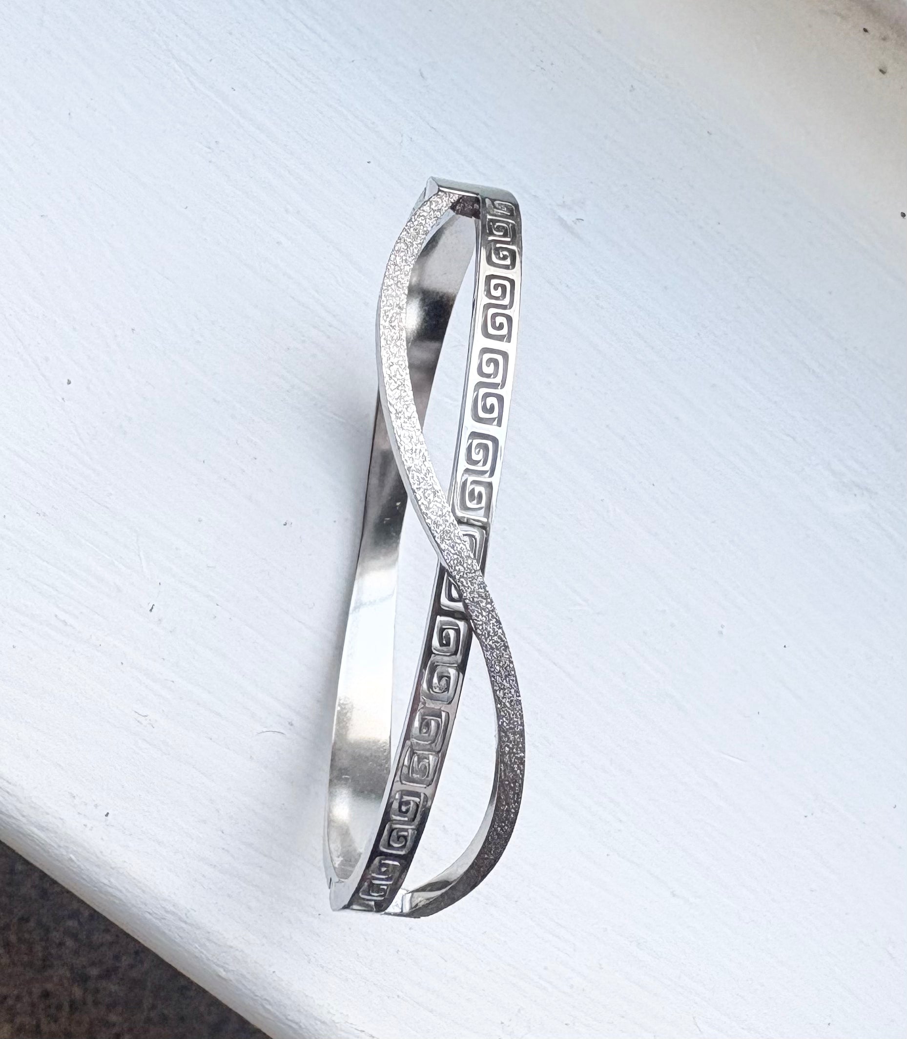 Silver bangle with a wave design and engrave pattern  