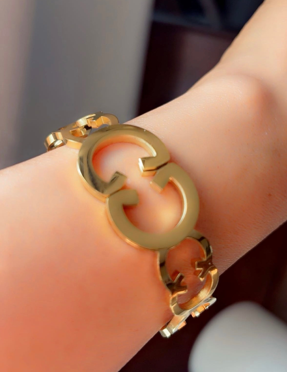 Gold bracelet with a distinctive design on a wrist.