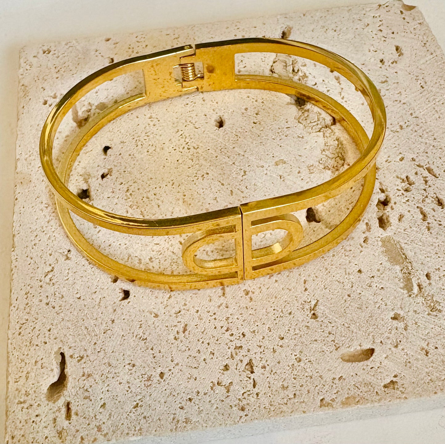 Gold bracelet on a textured beige surface