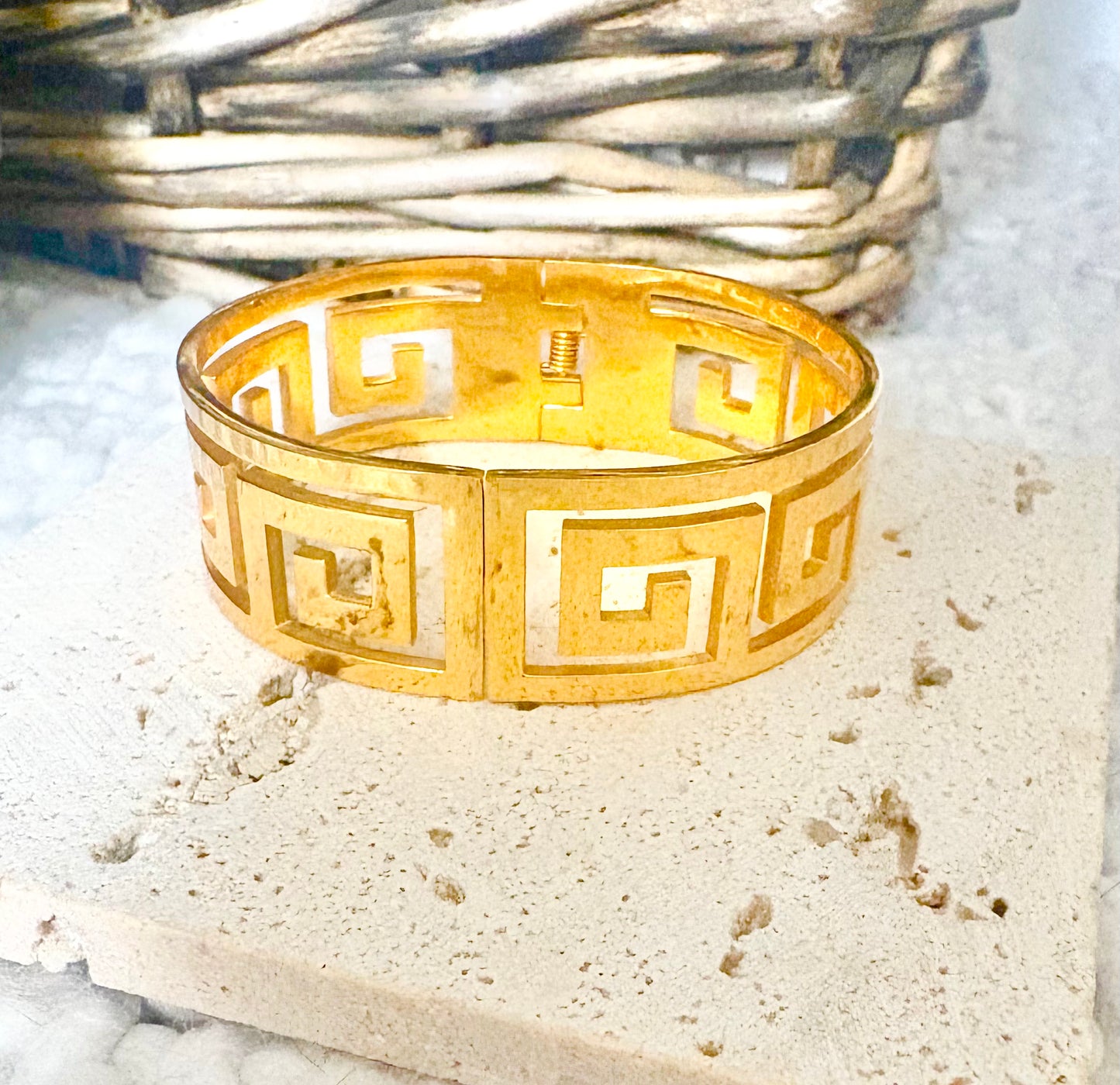 Gold bracelet with geometric pattern on a textured surface