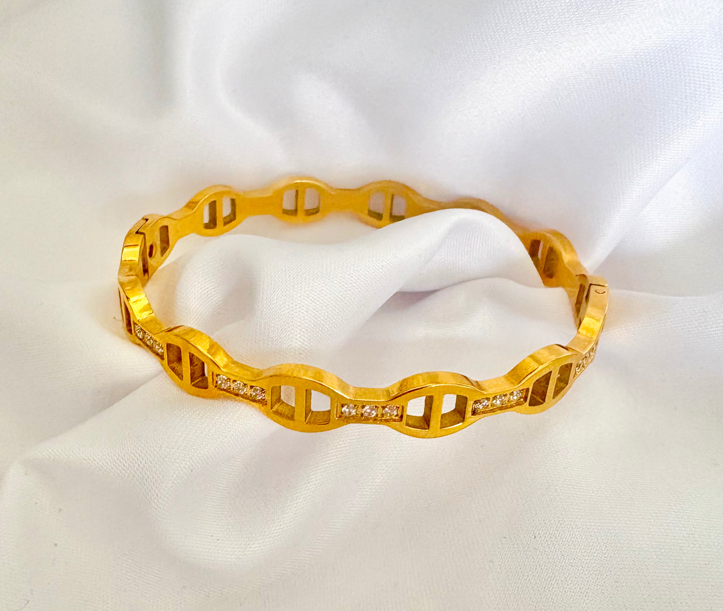 Gold bracelet with diamond accents on a white fabric background