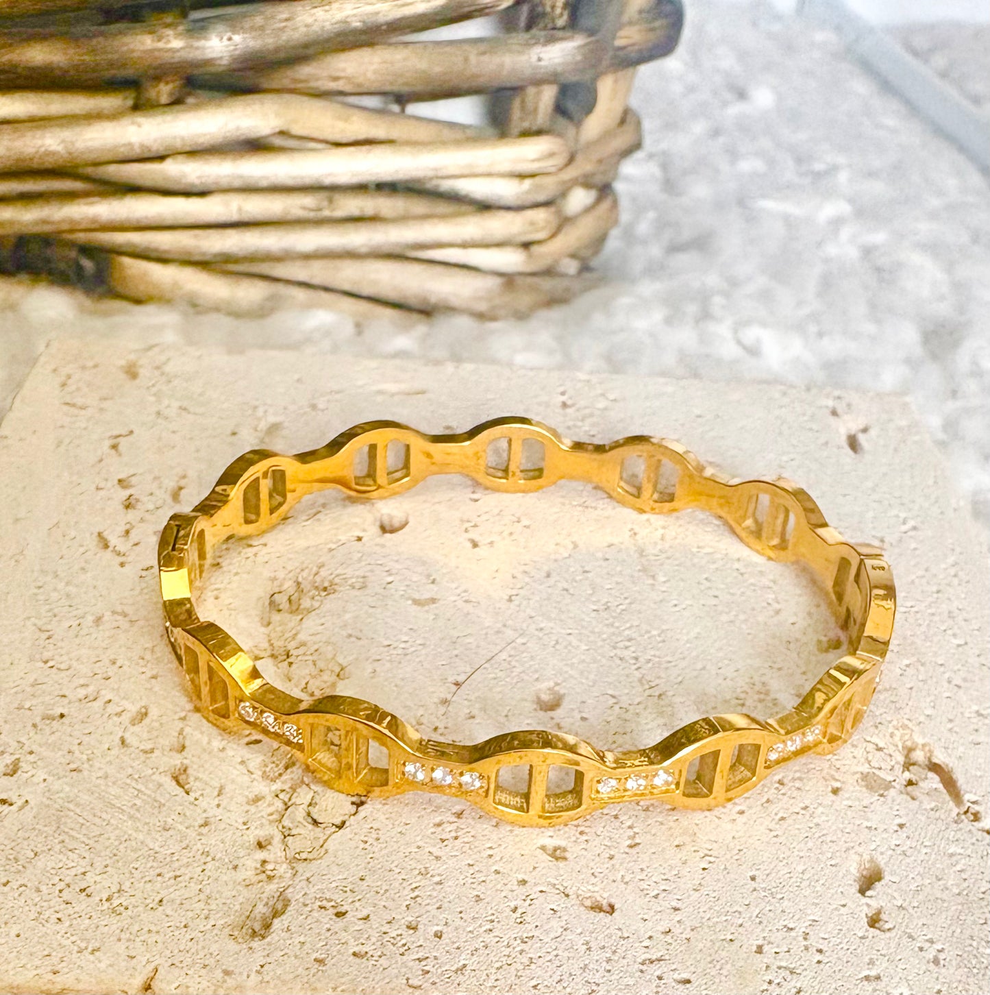 Gold bracelet with geometric design on a textured surface