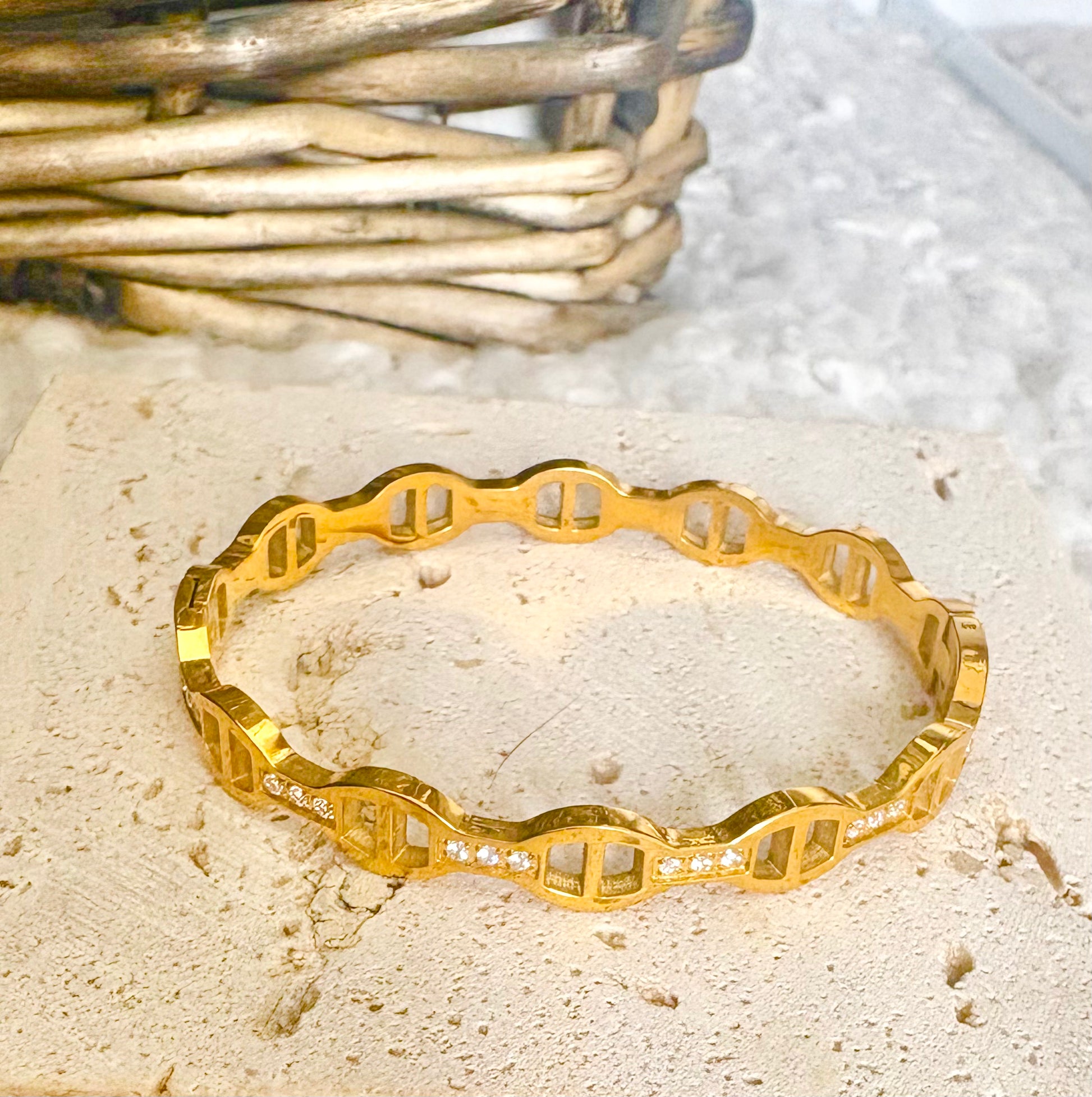Gold bracelet with geometric design on a textured surface