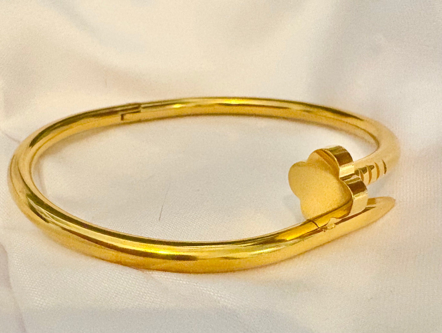 Gold bracelet with a heart-shaped clasp on a white fabric background