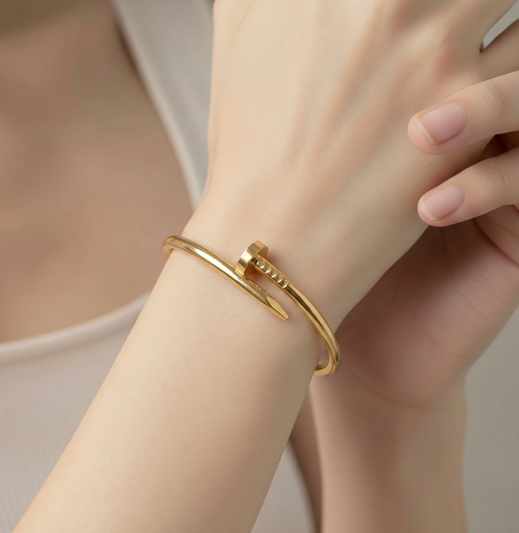 Gold bracelet on a wrist with a neutral background
