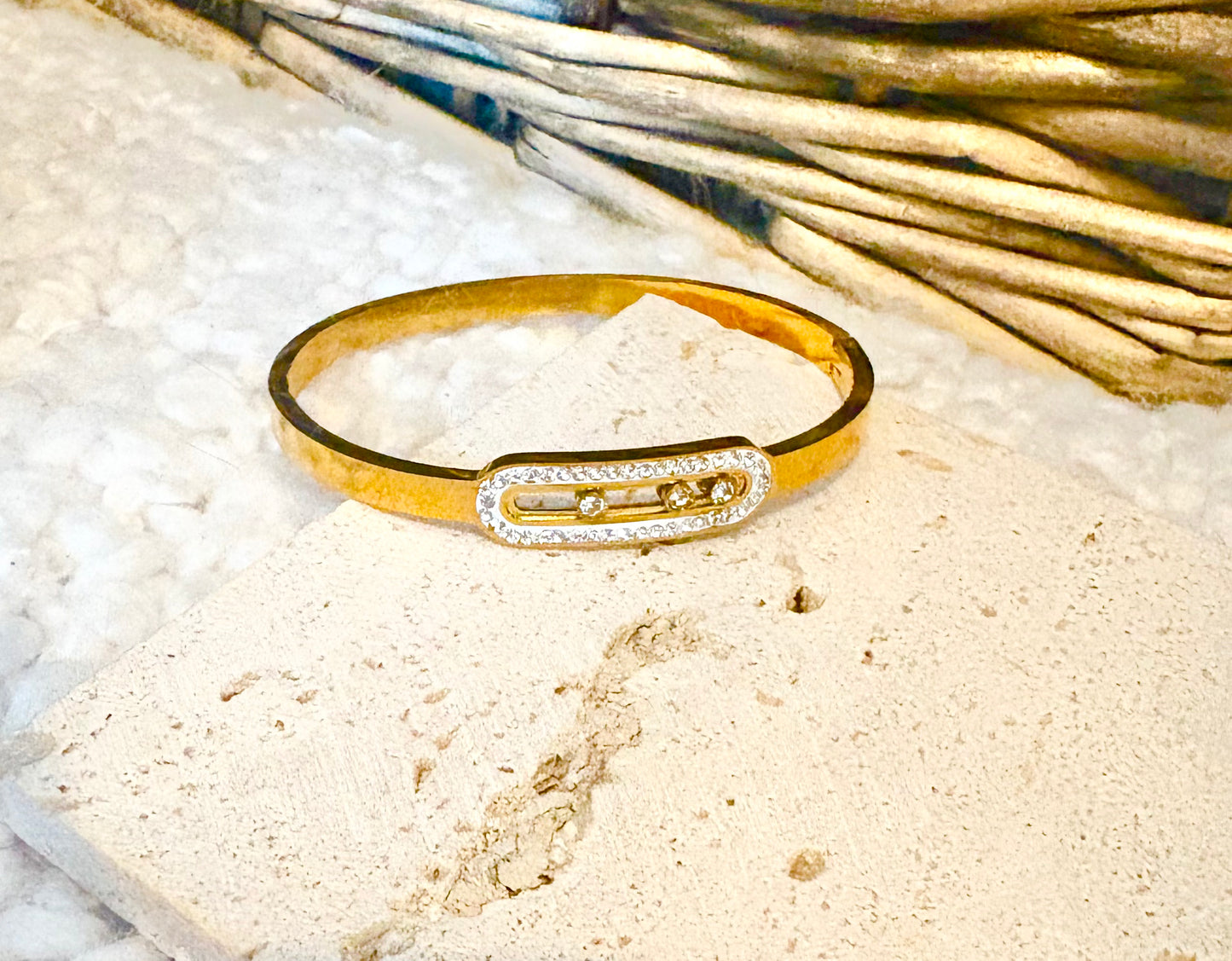 Gold bracelet with a diamond-like stone on a textured surface