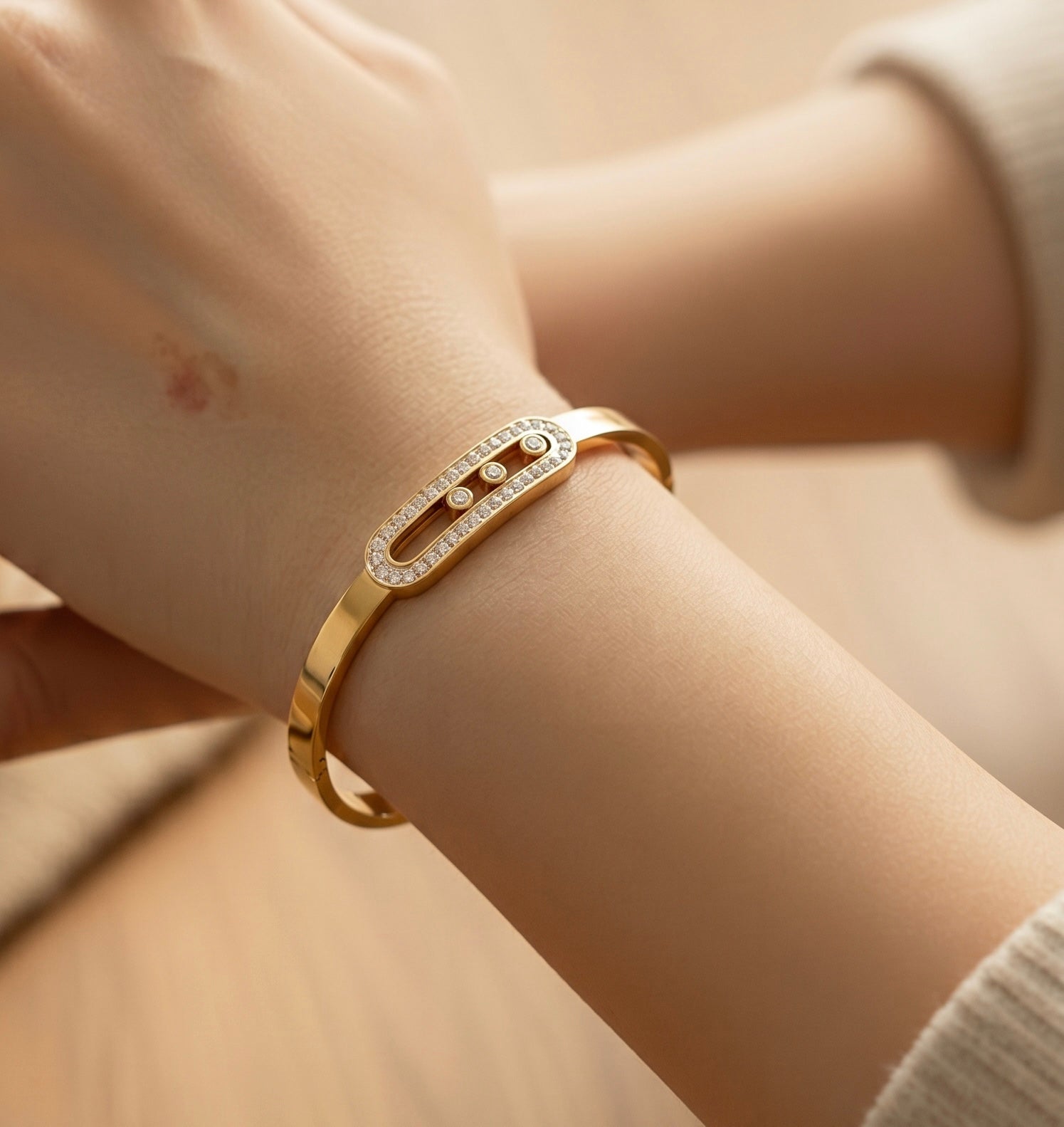 Gold bracelet with clear stones on a wrist against a neutral background