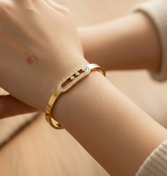 Gold bracelet with clear stones on a wrist against a neutral background
