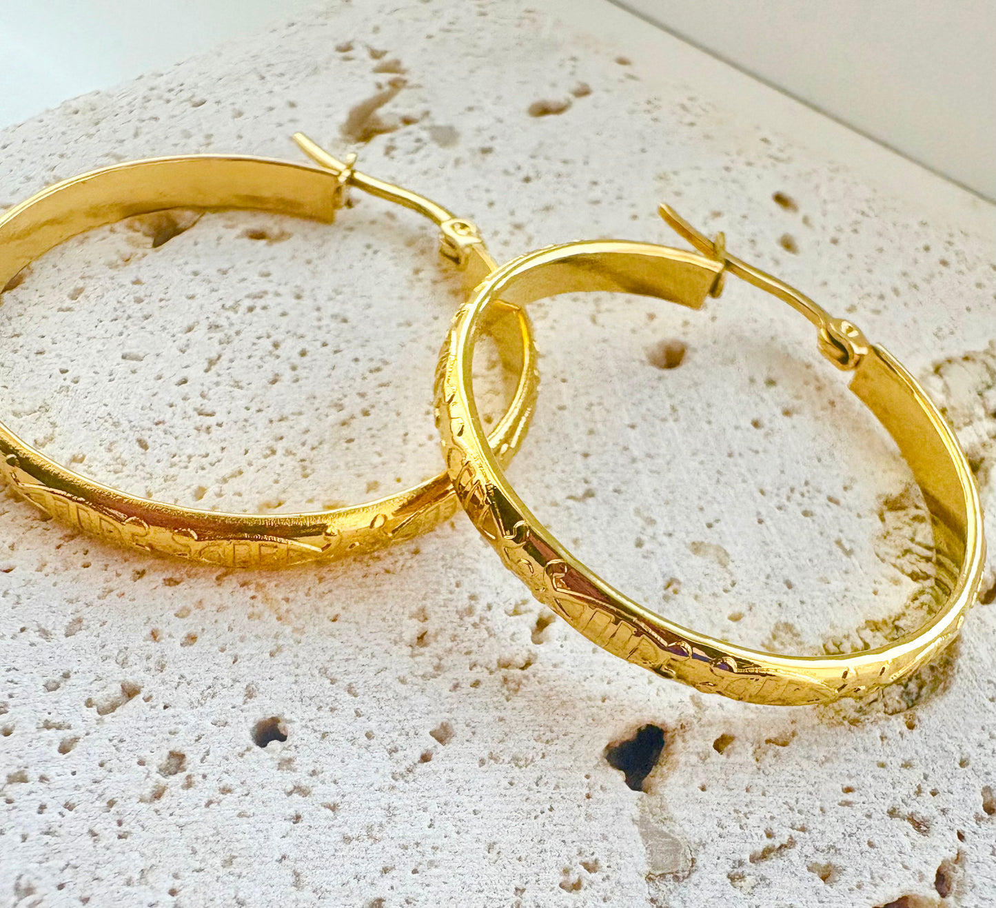 Gold hoop earrings on a textured surface