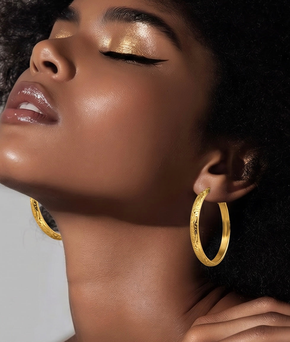 Close-up of a woman wearing gold hoop earrings with a neutral background