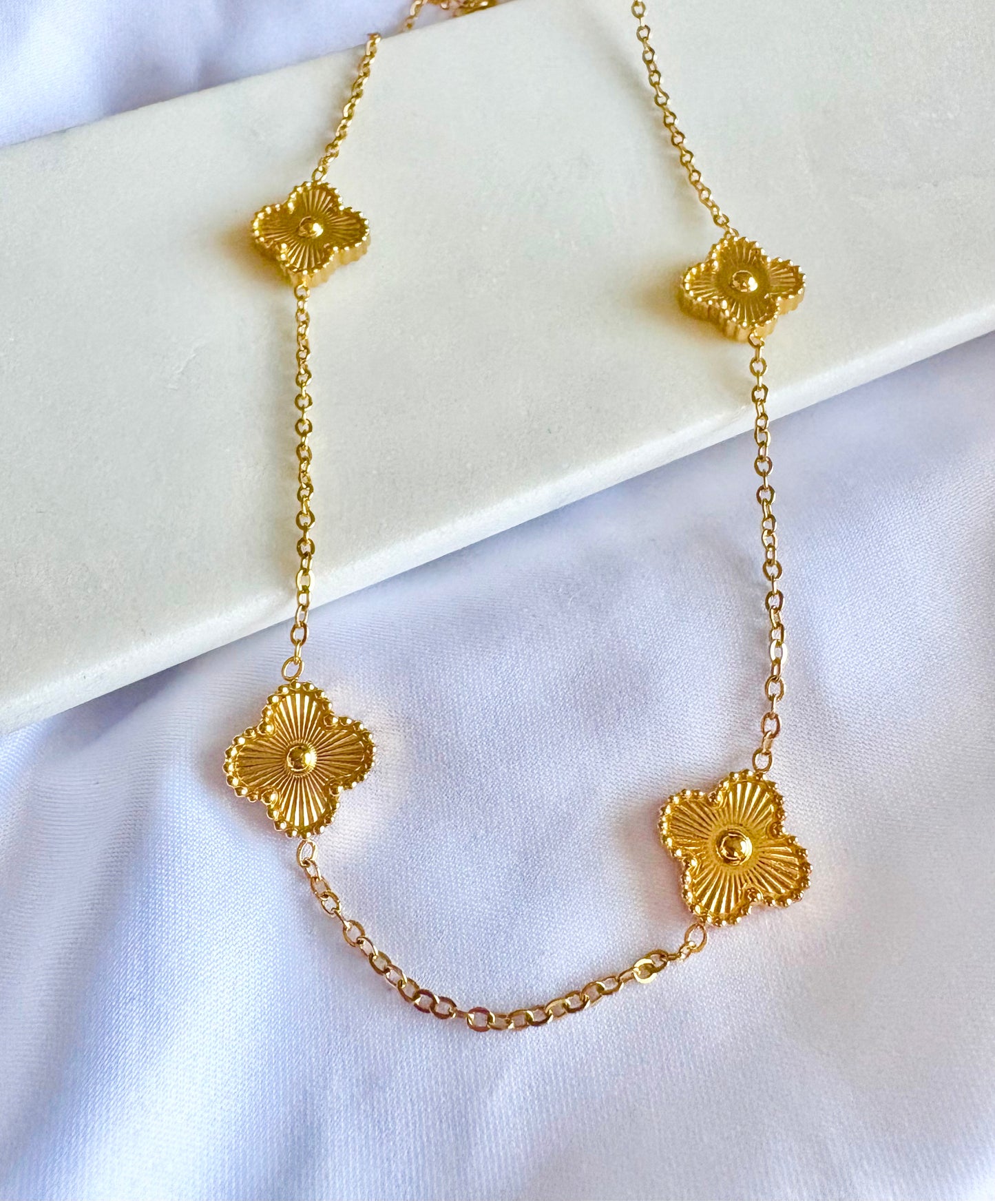 Gold Clover Necklace on a white fabric