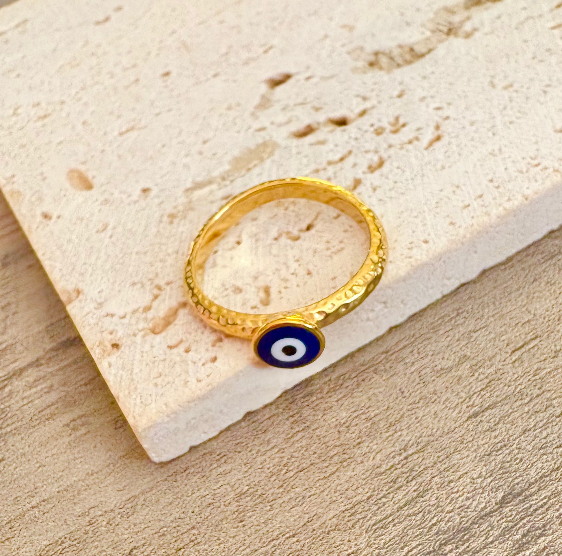 A gold ring with a circular blue, white, and black evil eye charm,