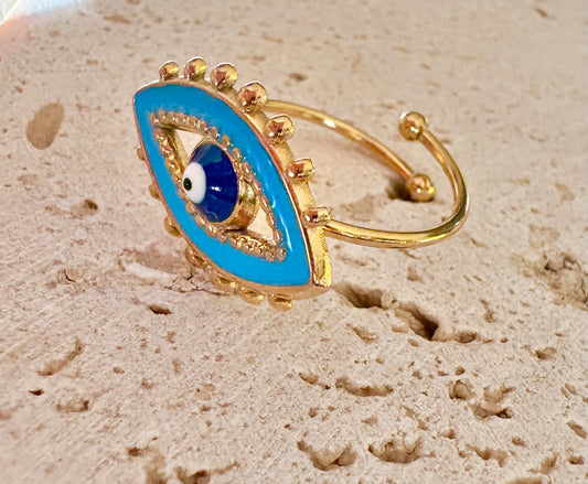 A gold-plated open ring featuring a large blue enamel evil eye design with a central white and black bead
