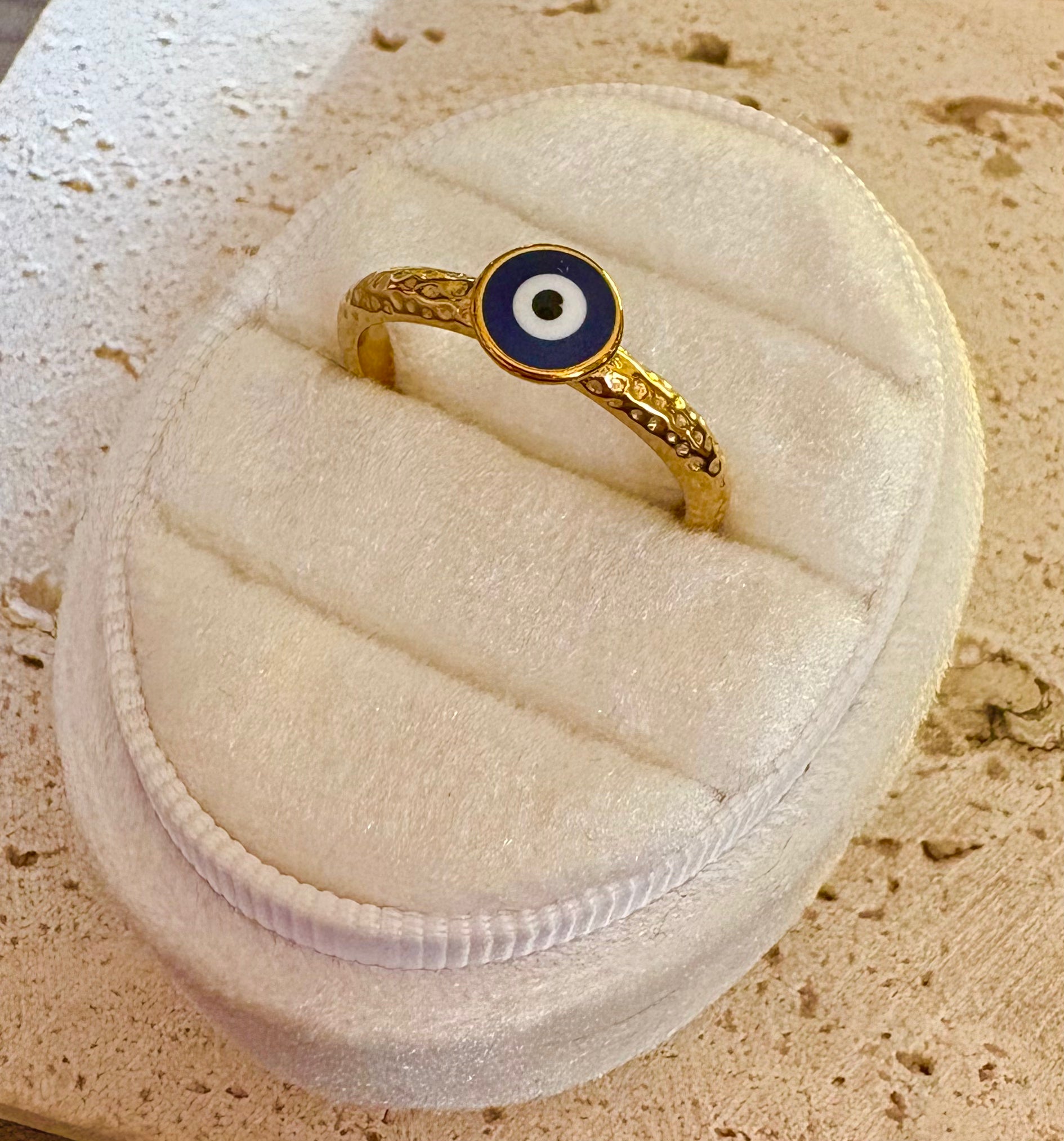 A gold ring with an evil eye motif featuring blue, white, and black concentric circles