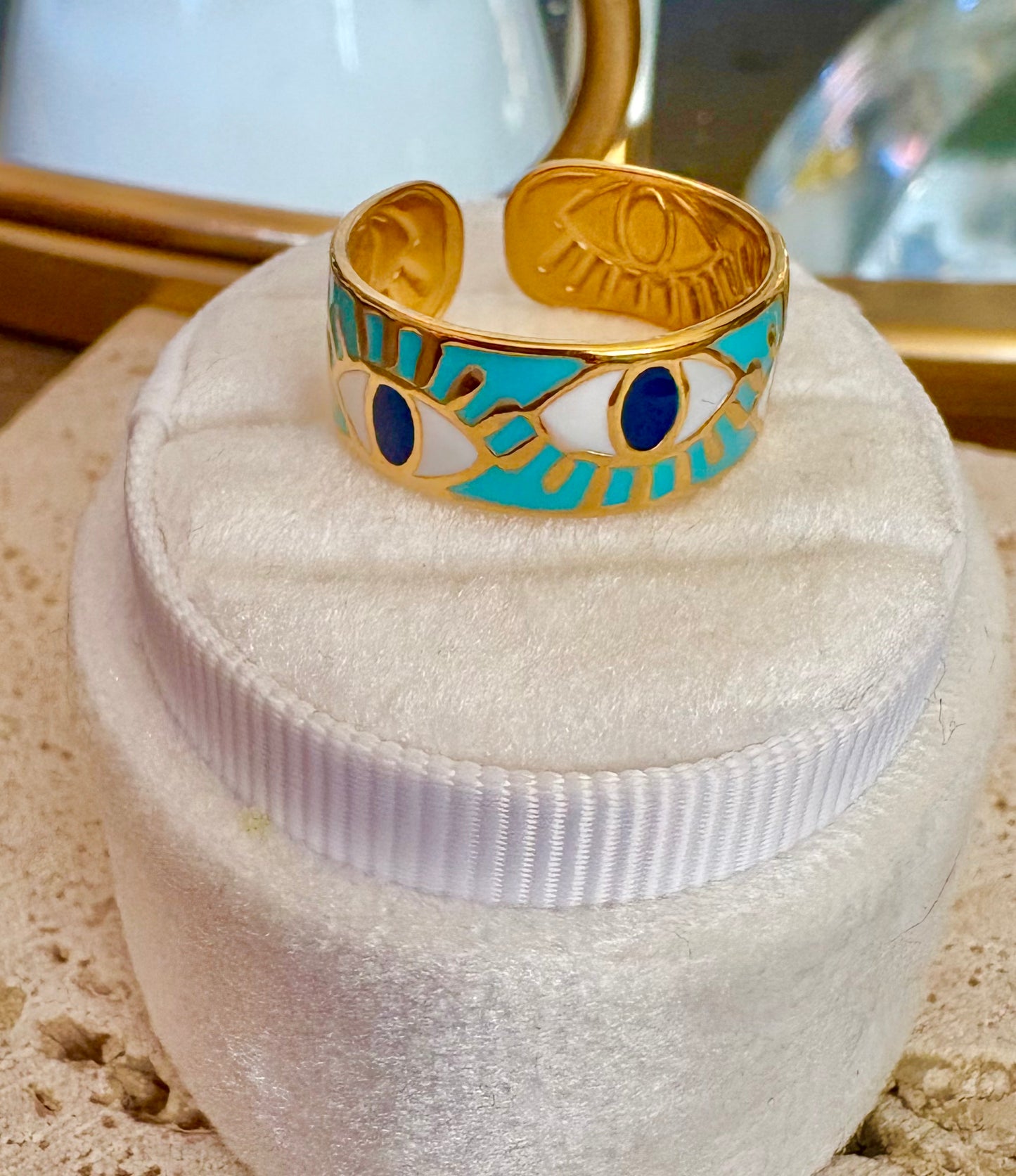 A gold ring with turquoise and white enamel eye motifs