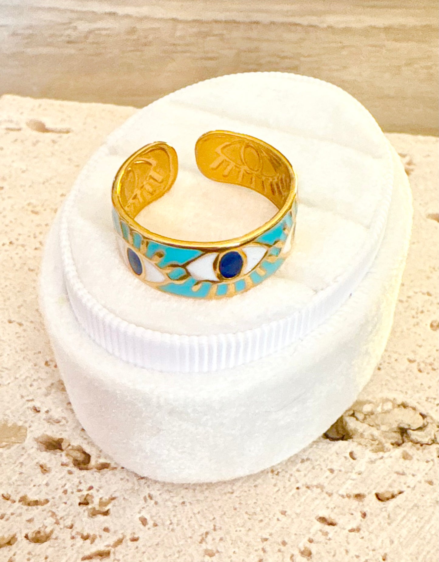 A gold cuff ring with turquoise enamel and evil eye motifs.