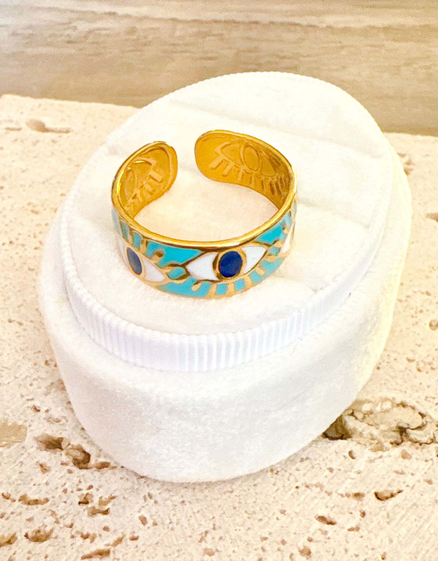 A gold cuff ring with turquoise enamel and evil eye motifs.
