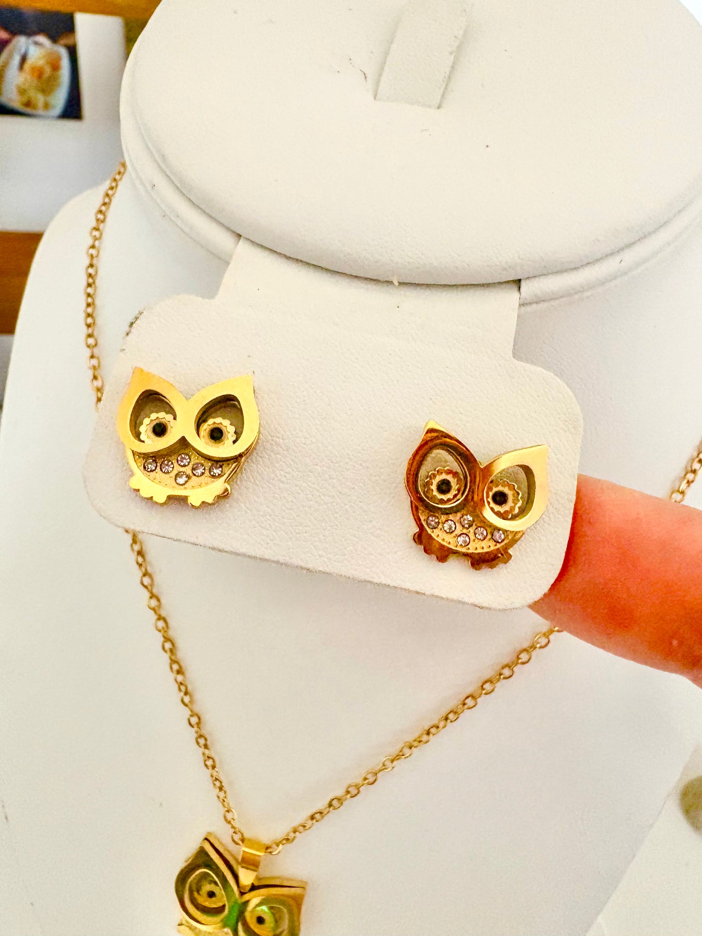 Gold owl stud earrings and matching owl pendant necklace displayed on a white jewelry stand