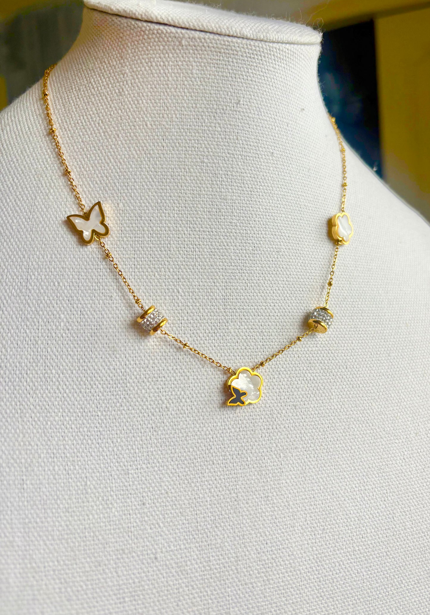A delicate gold chain necklace displayed on a white fabric jewelry bust. 