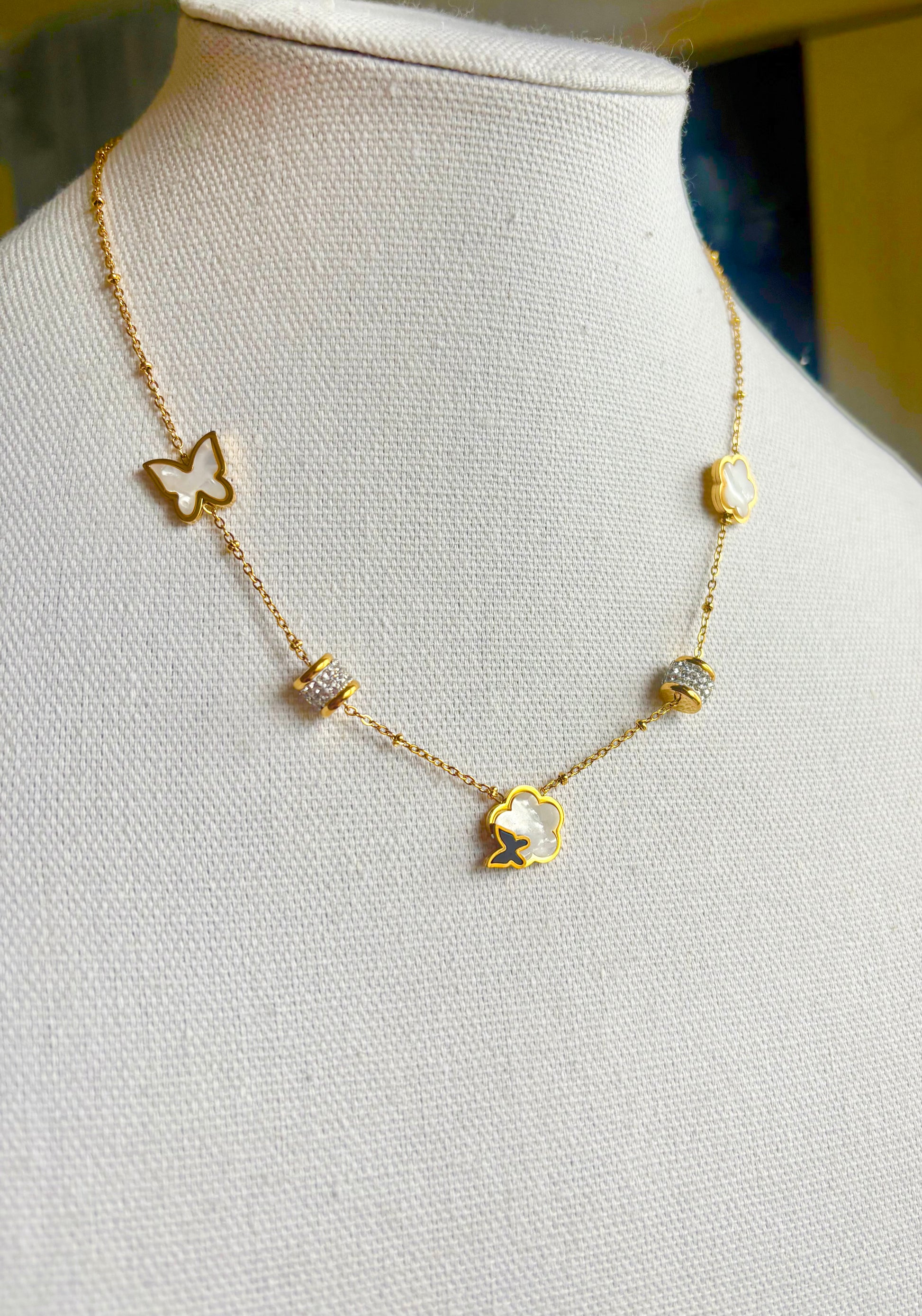 A delicate gold chain necklace displayed on a white fabric jewelry bust. 