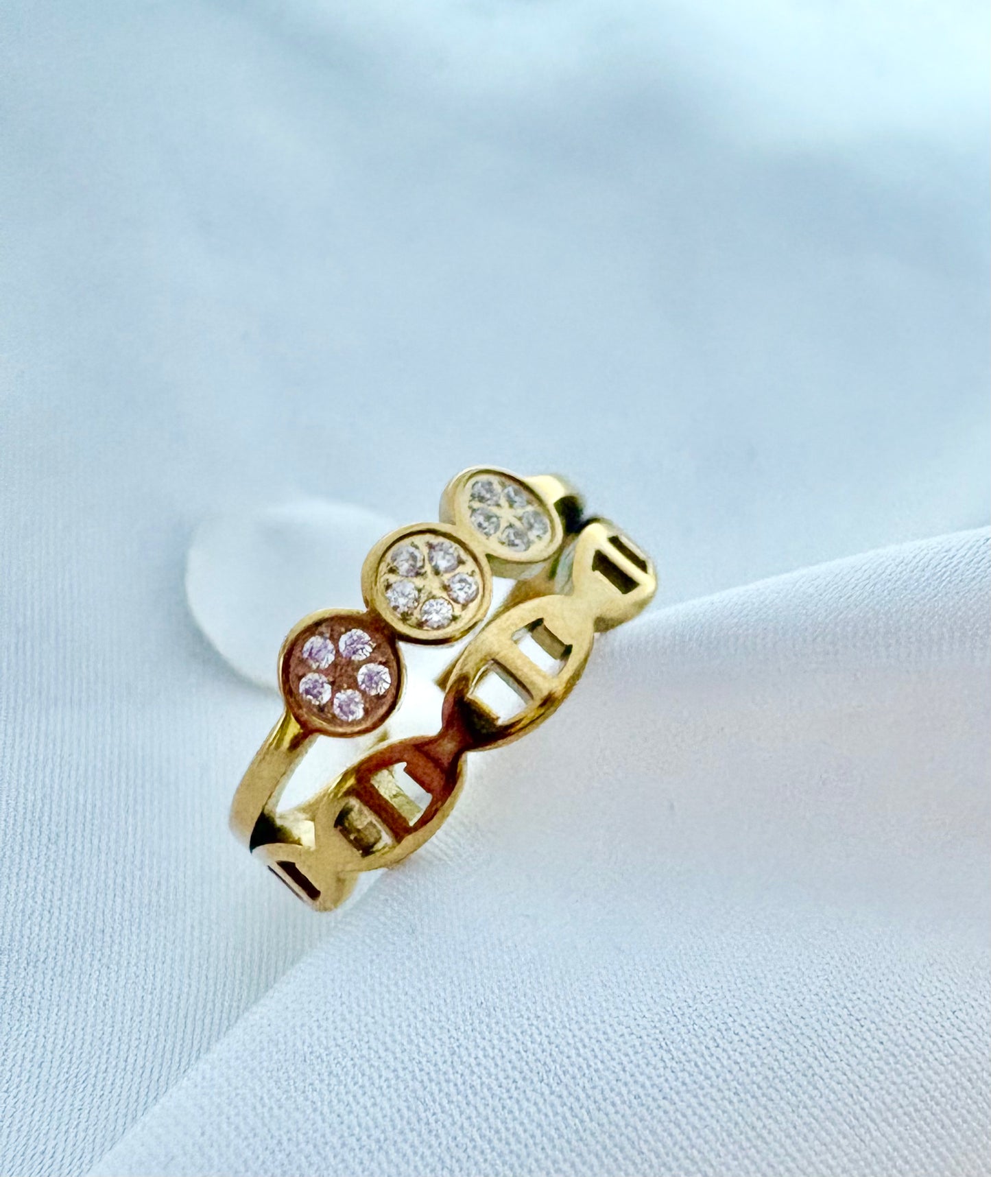 A gold ring with three oval clusters of zircon gemstones.