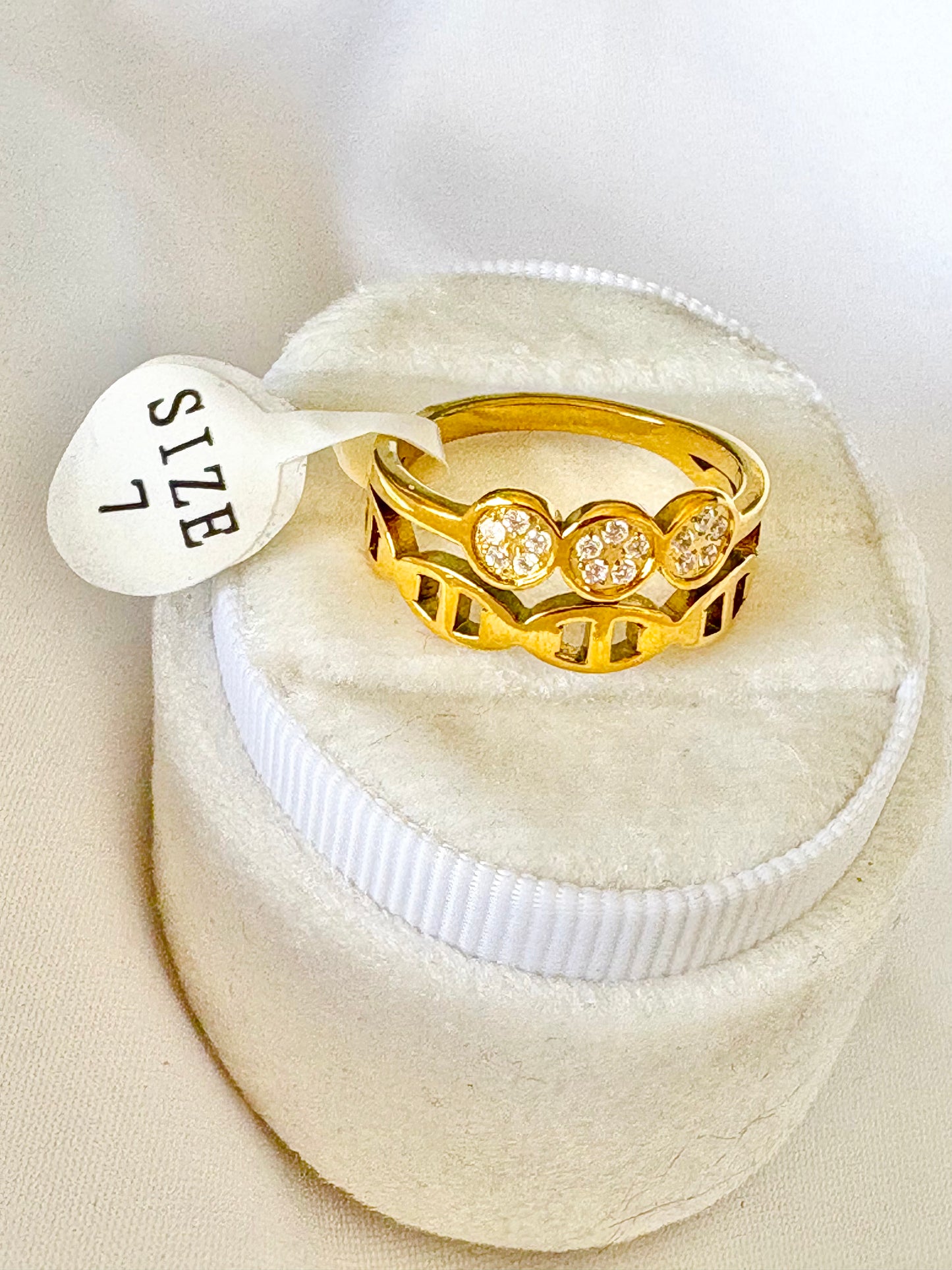 A gold ring with three round zircons settings. 'SIZE 7' 